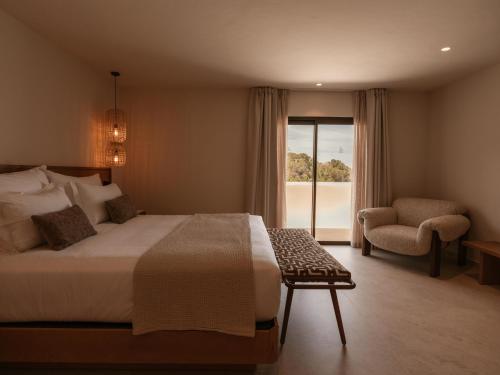 a bedroom with a bed and a chair and a window at Besai Ibiza Boutique Hotel - New Opening in San Jose