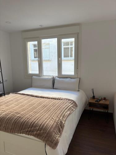 a white bedroom with a large bed with a window at Ribeira Penélope in Ribeira