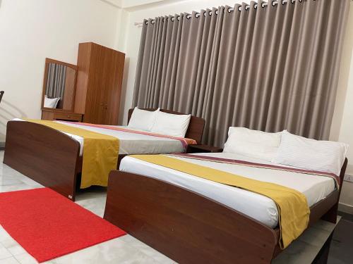 two beds in a hotel room with a red carpet at The Dream City Hotel in Kilinochchi