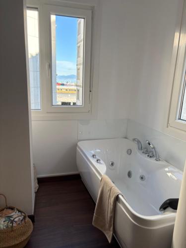 a white bathroom with a tub and a window at Ribeira Penélope in Ribeira