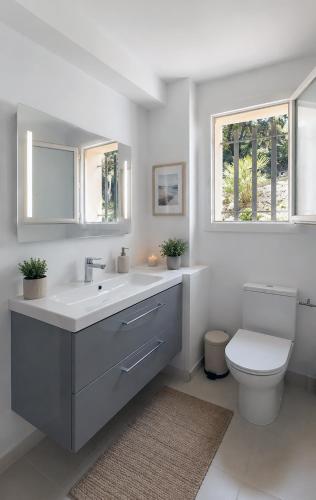 a bathroom with a sink and a toilet and a window at Villa Bellevue, magnifique vue mer! Piscine chauffée, à10 mns de la plage et du centre! in Cavalaire-sur-Mer
