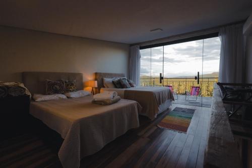 a hotel room with two beds and a large window at Govinda House in Alto Paraíso de Goiás