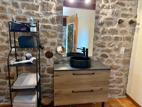 a bathroom with a sink and a stone wall at Le Gîte de Couturas in Saint-Hilaire-les-Courbes