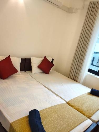 a bedroom with two beds with red pillows and a window at Ayubo Villa in Ja-Ela
