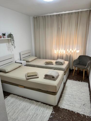 a bedroom with two beds and a chair at Chalet PuigVal 50m de la playa in Valencia