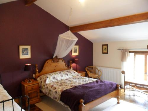 a bedroom with a king sized bed with purple walls at Le Tilleuil in Combiers