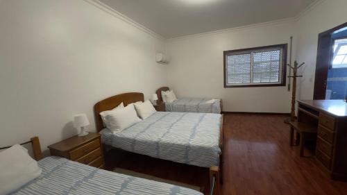 a bedroom with two beds and a dresser and a desk at Hotel Reels - Residencial O TRINDADE in Águeda