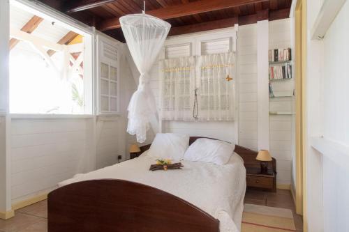 - une chambre avec un lit dans une pièce aux murs blancs dans l'établissement L'escapade, à Sainte-Anne