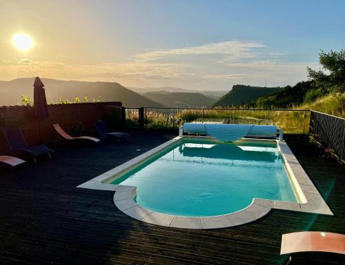 a small swimming pool with two chairs and the sunset at la Ferme de Vazerat in Massiac