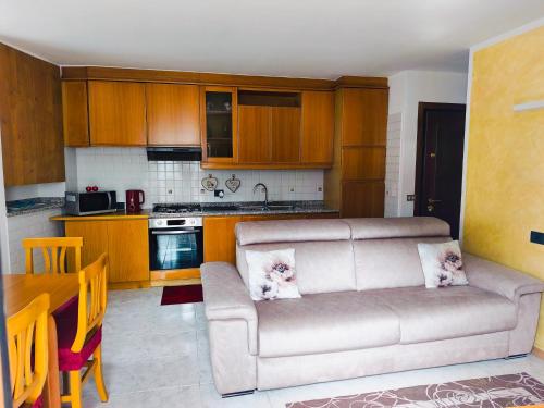 a living room with a couch and a kitchen at NicoMeli Home in Dimaro