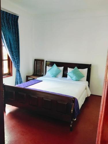 a bedroom with a large bed with blue pillows at The Train View in Nuwara Eliya