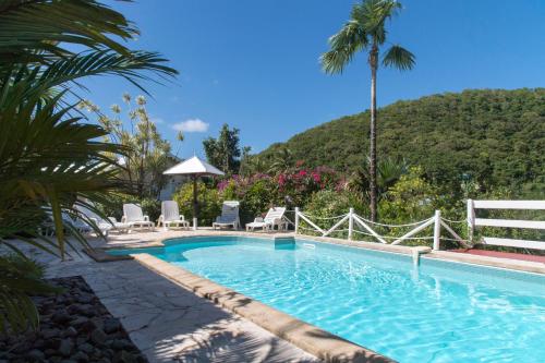 a swimming pool with chairs and a mountain in the background at L'escapade in Sainte-Anne