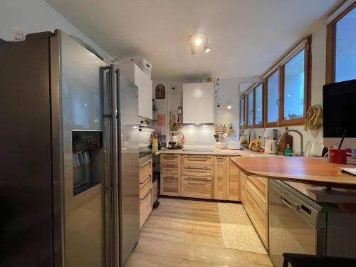 a kitchen with a stainless steel refrigerator and wooden cabinets at Montana Appartment in Planay