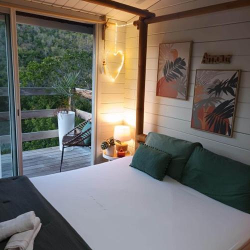 a bedroom with a white bed and a balcony at Cabanes rêve d'enfant in Les Anses-dʼArlets