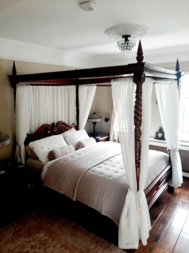 a bedroom with a canopy bed with white curtains at Riverside Lodge in Carlingford