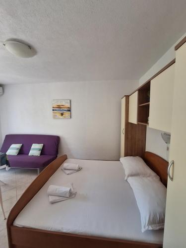 a bedroom with a bed and a purple couch at Studio apartmani Ante in Zaostrog