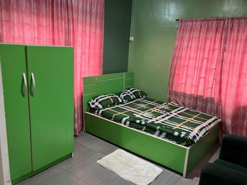 a bedroom with a green bed and a red curtain at Electra Serviced 1 Bedroom Apartment, Lagos in Iju Junction