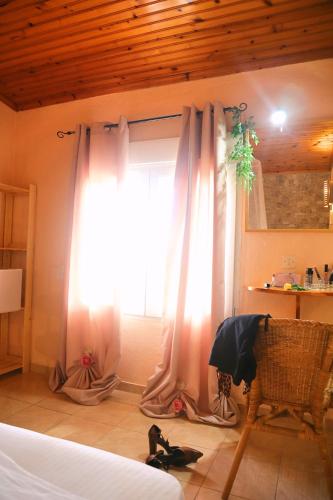 a bedroom with a bed and a window with curtains at La Rosalie in Astris
