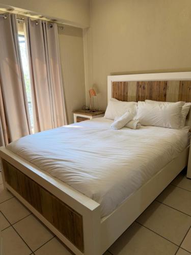a large white bed in a room with a window at Caly Luxury Home in Nelspruit