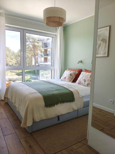 a bedroom with a bed and a large window at Apartament VerdeMar in Rowy