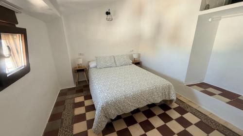 a bedroom with a bed in a room with a checkered floor at La Casa del Rey Alhamar in Arjona