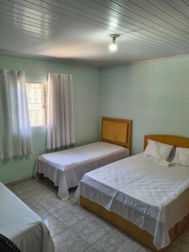 a bedroom with two beds and a window at Recanto Vila Madalena in Caçapava