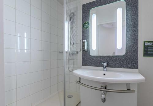 a white bathroom with a sink and a mirror at B&B HOTEL Versailles Le Chesnay in Le Chesnay