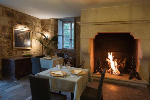 a dining room with a table and a fireplace at Hotel Pazo de Bieite in Boimorto