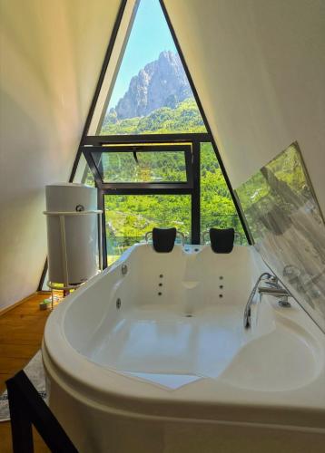 een badkamer met een badkuip en een groot raam bij Arditi's Chalets in Bogë