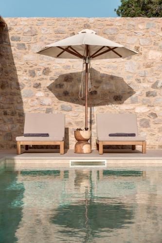two chairs and an umbrella next to a swimming pool at Elion Private Pool Villas in Kos