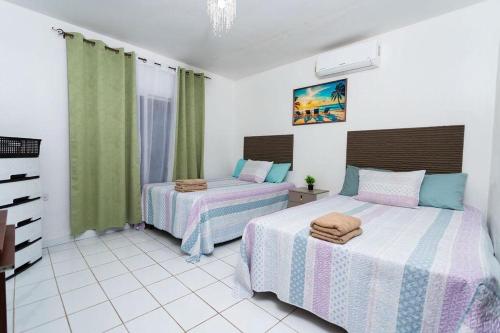 two beds in a bedroom with green curtains at Casa Herminia in Omoa
