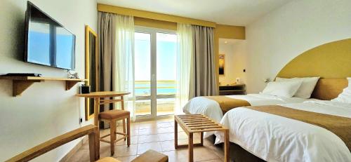 a hotel room with two beds and a large window at Ostrea - Lagune de Oualidia in Oualidia