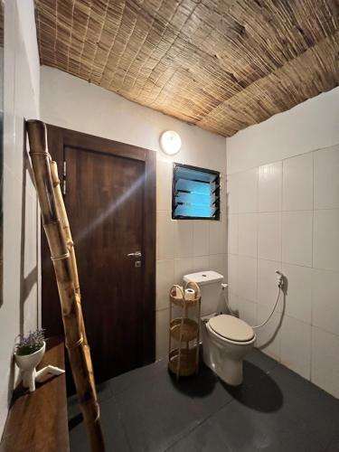 a bathroom with a toilet and a wooden door at Shadamaltess in Azuretti