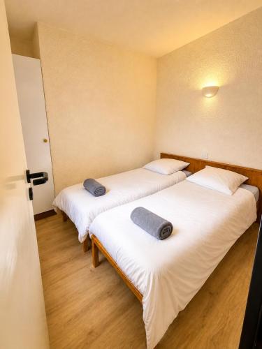 two beds in a room with white sheets and pillows at L'évasion montagnarde - résidence loisirs - garage in Lélex