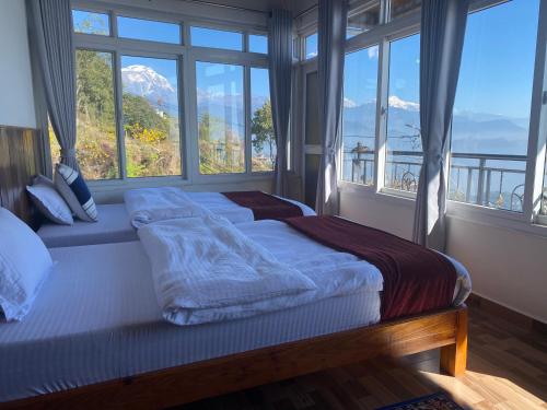 a bedroom with a large bed with large windows at Panoramic View Guest House Sarangkot in Pokhara