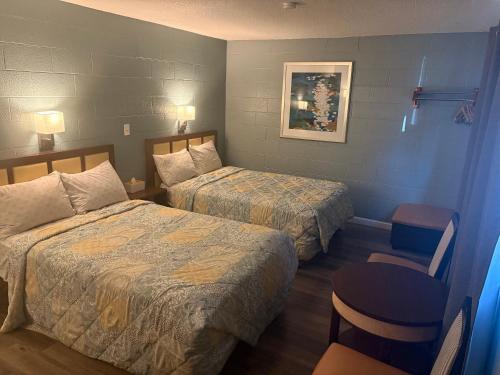 a hotel room with two beds and a chair at Lamplighter Motel in Longmont