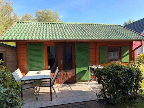 a small green house with a table and chairs at Bungalow am Hafen in Dierhagen