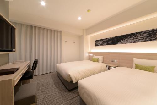 a hotel room with two beds and a television at Vessel Inn Shinsaibashi in Osaka