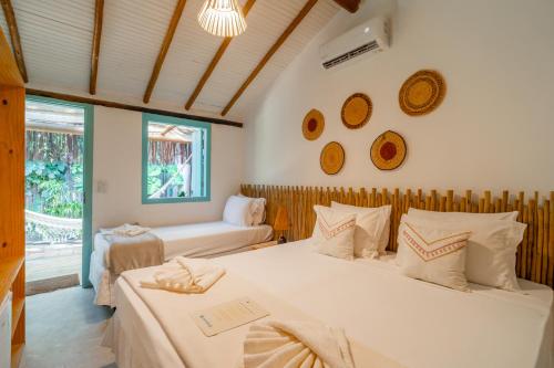 a bedroom with two beds and a window at Pousada do Rio Caraíva in Caraíva