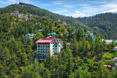 a building on the side of a hill with trees at Aachman Nature Valley Resort MASHOBRA in Shimla