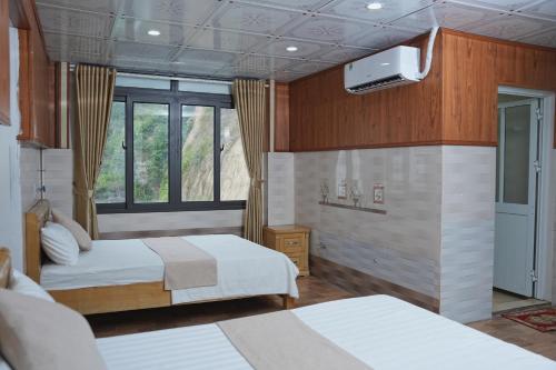 a bedroom with two beds and a tv on the wall at CATBA PANDORA Hotel & Travel in Cat Ba