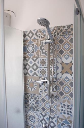 a shower in a bathroom with blue and white tiles at Appartamento sul mare in Belmonte Calabro