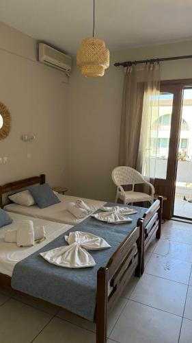 two beds in a bedroom with two tables with napkins at Roula's Apartment in Limenaria