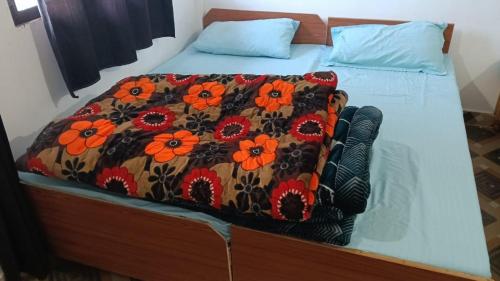 a bed with a blanket with orange flowers on it at Punchkedar in Phata