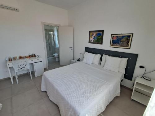a bedroom with a white bed and a desk at Bouganvillea in Senigallia