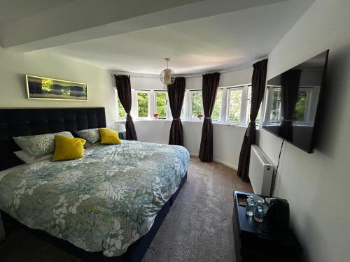 a bedroom with a bed with yellow pillows and windows at Hadrian House in East Preston