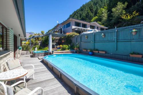 a swimming pool in a backyard with a table and chairs at Coronet View Accommodation in Queenstown