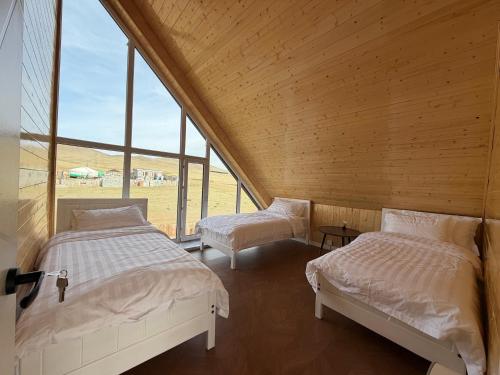 two beds in a room with large windows at Healing stay hostel in Dzuunmod