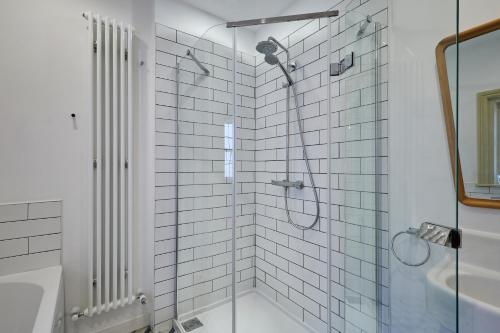 a bathroom with a shower with white tiles at Sandy Toes in Sandsend