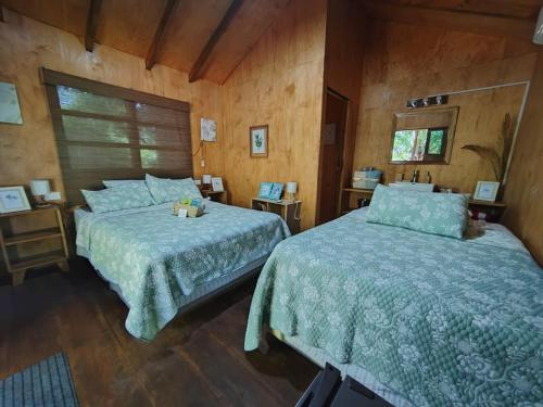 two beds in a bedroom with wooden walls at Jimmys cabins in La Periquera
